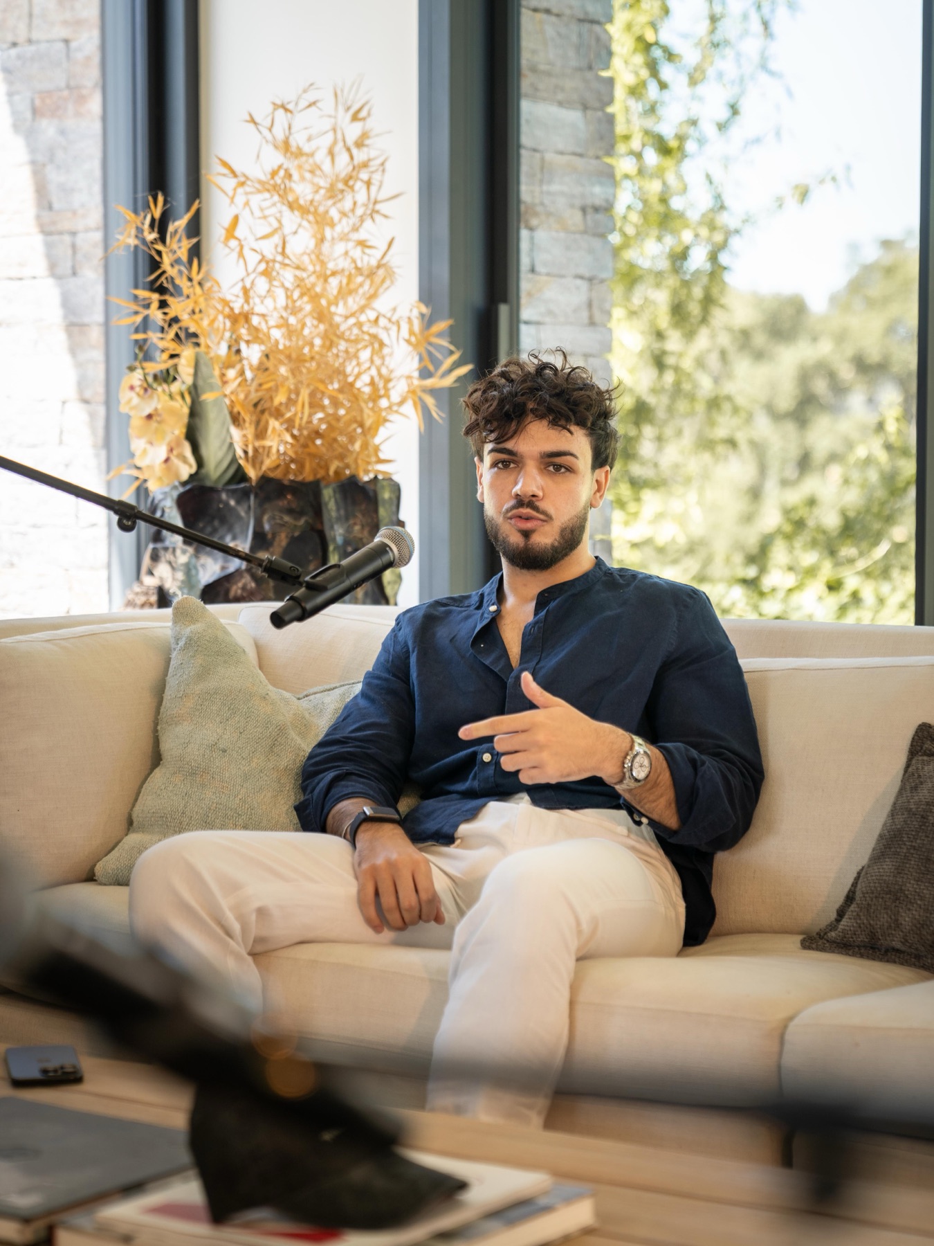 Nicolò during a filmed interview, seated on a sofa with a microphone in frame