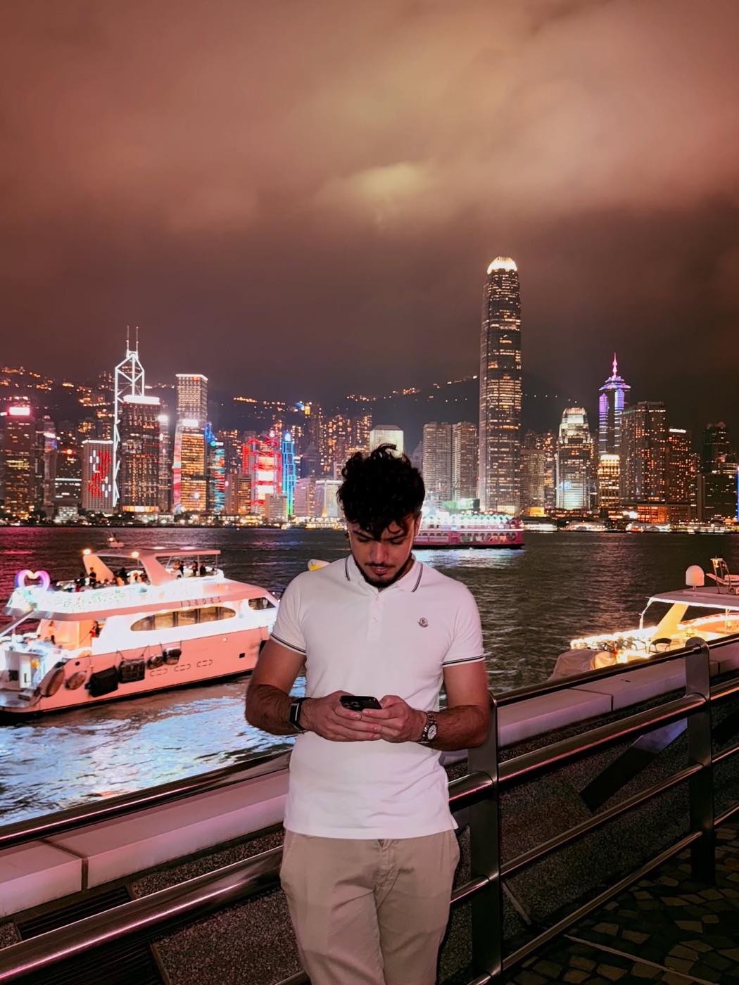 Nicolò on his phone at night in front of the Hong Kong skyline